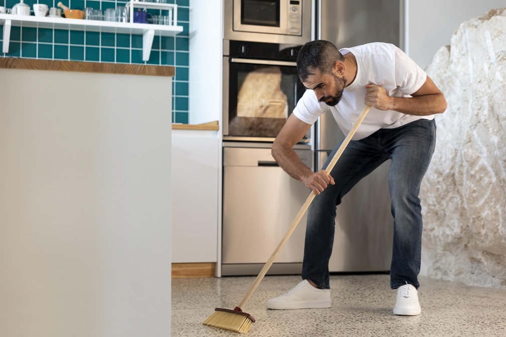 barriendo con la escoba los lugares más dificiles