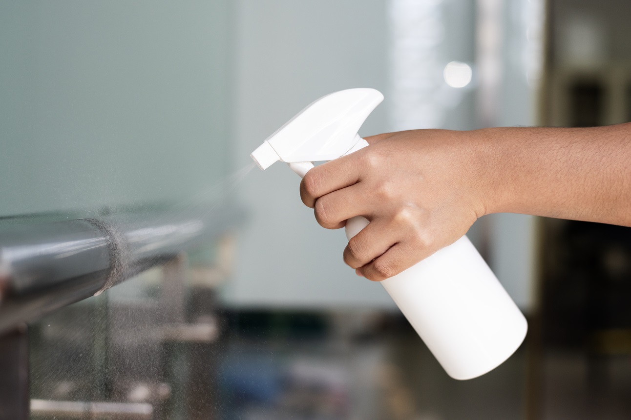 tipos de desinfectantes y sus usos en el hogar rociando desinfectante en una supericie metalica