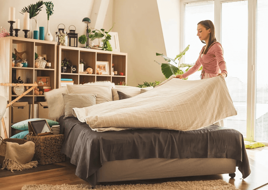Mujer ordenando la cama de su hogar