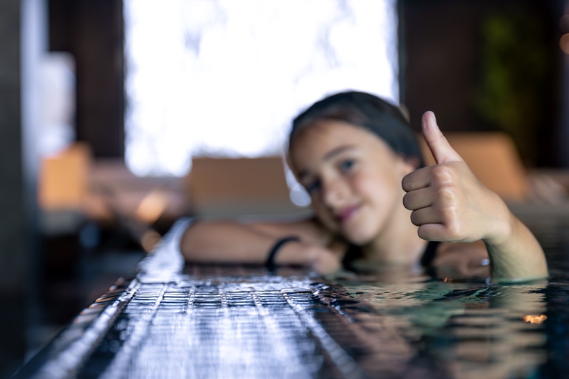 niña con pulgar hacia arriba en la piscina