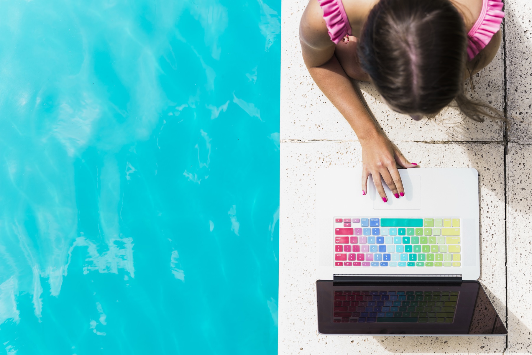mujer joven con el computador junto a la pisicna, teclas de colores como una carta de color